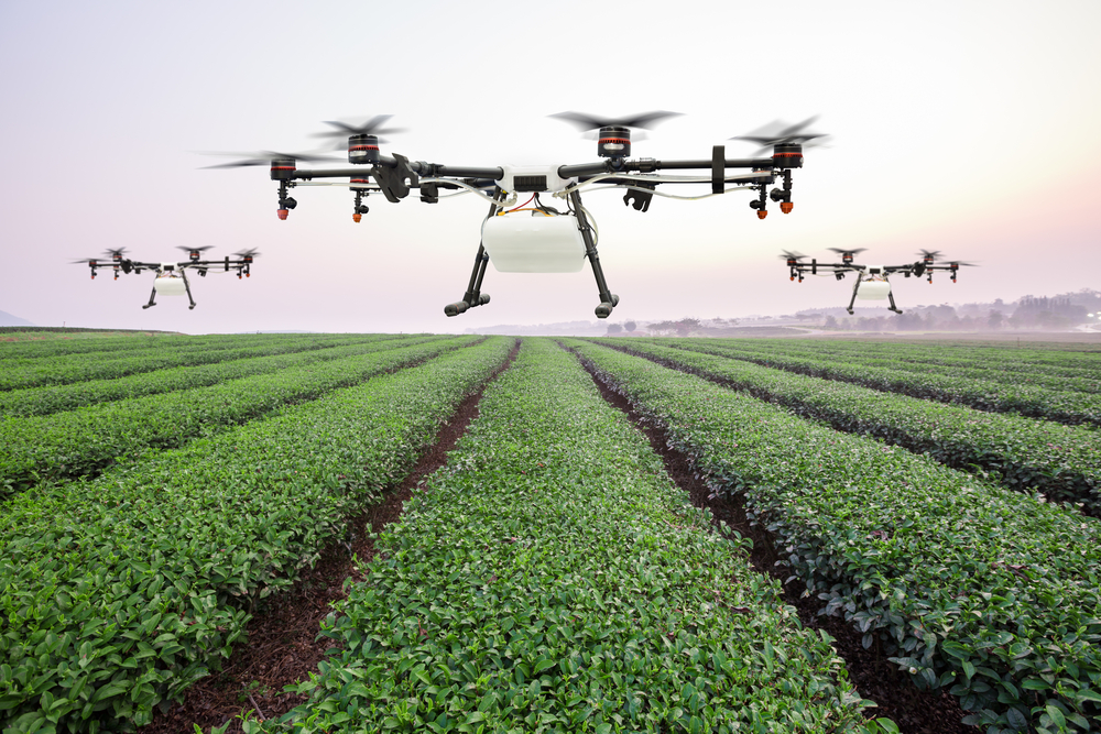 Three big drones hovering over a field